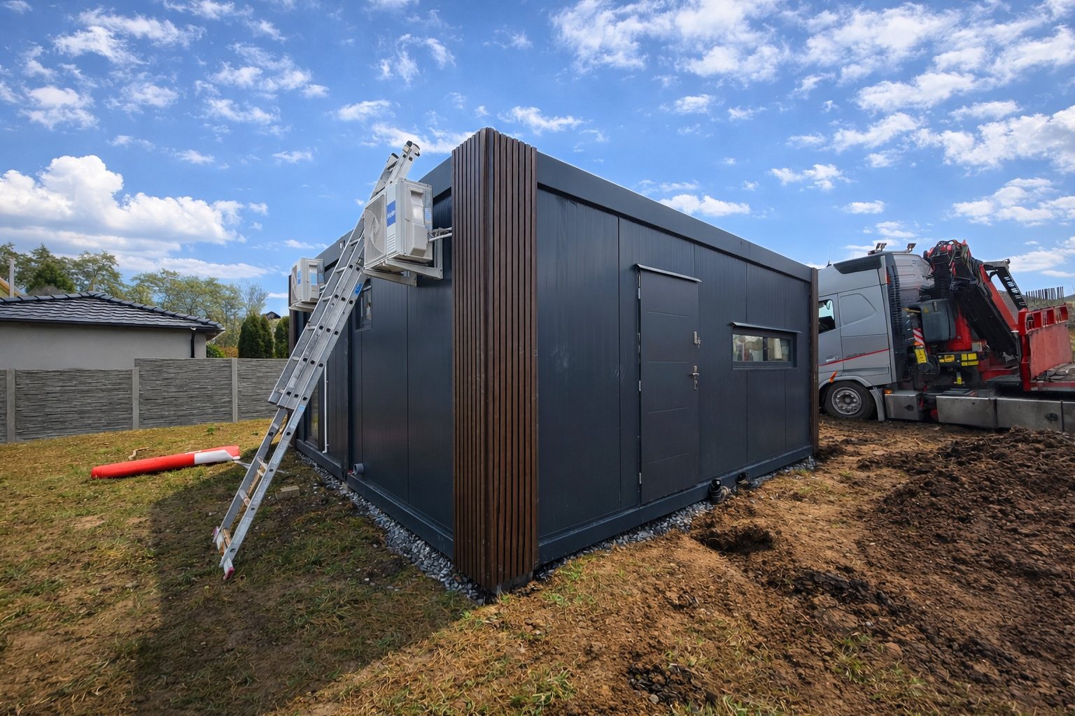 Boční pohled na hotový modulový dům Lucy 6×6 s tmavou fasádou a obkladem v dekoru dřeva